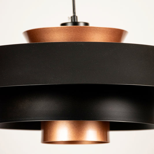 Black and copper metal pendant light closeup highlighting modern layered craftsmanship.