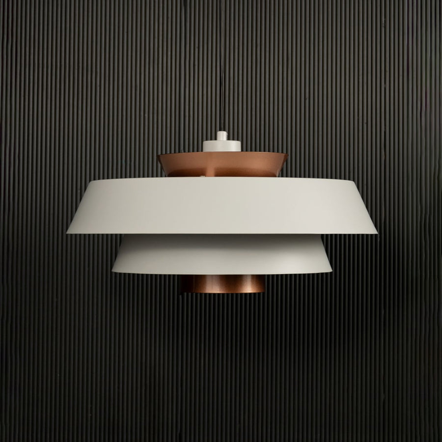 White and copper pendant light displayed on dark background with lights off emphasizing elegant modern metal craftsmanship.