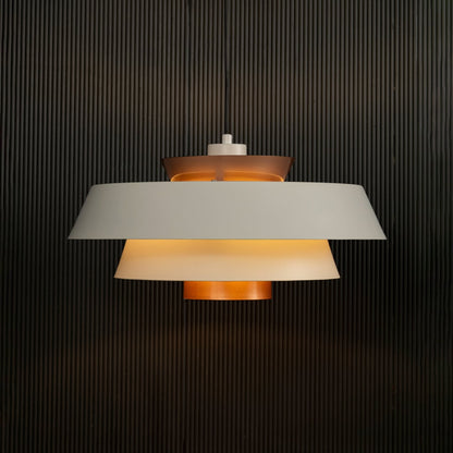 Elegant white and copper pendant hanging light illuminated against dark background highlighting its sleek layered modern industrial design.