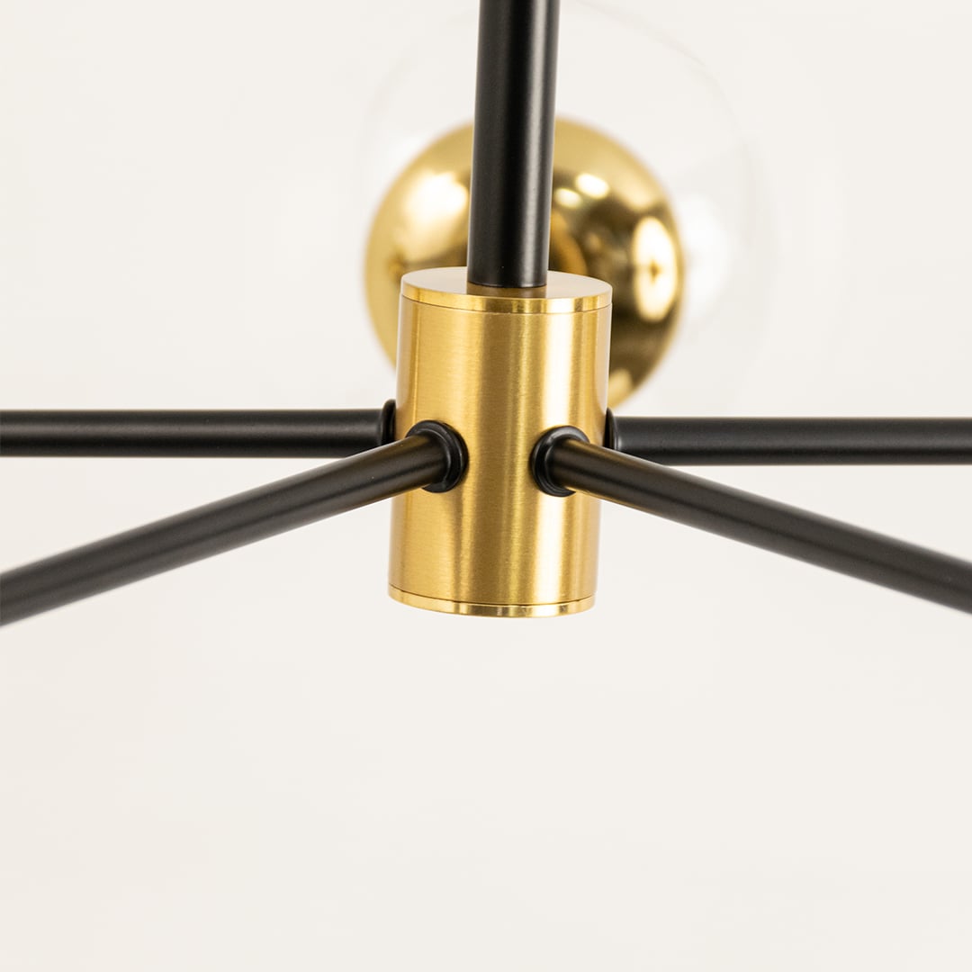 Close-up view of a modern chandelier fixture featuring black metal rods and a gold brass connector for an elegant lighting design.