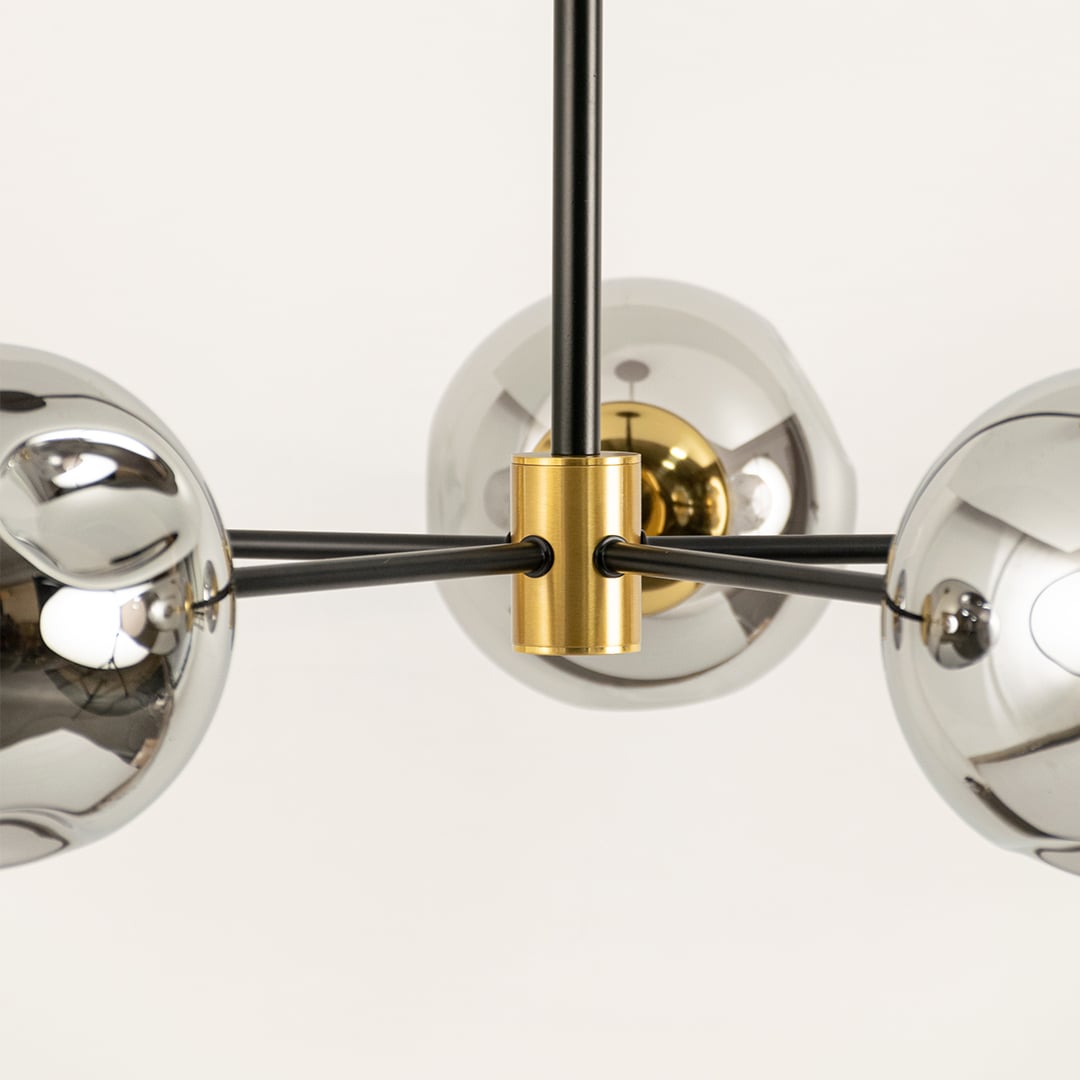 Closeup of modern chandelier arm with chrome glass globes and gold metal connector highlighting luxury finish and detailing.