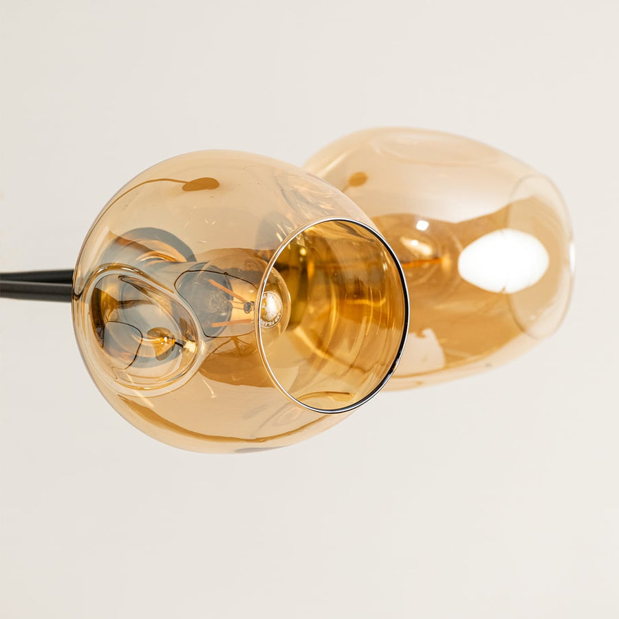 Closeup of amber glass globe light shade showing smooth curved surface warm tint and premium glass craftsmanship detail.