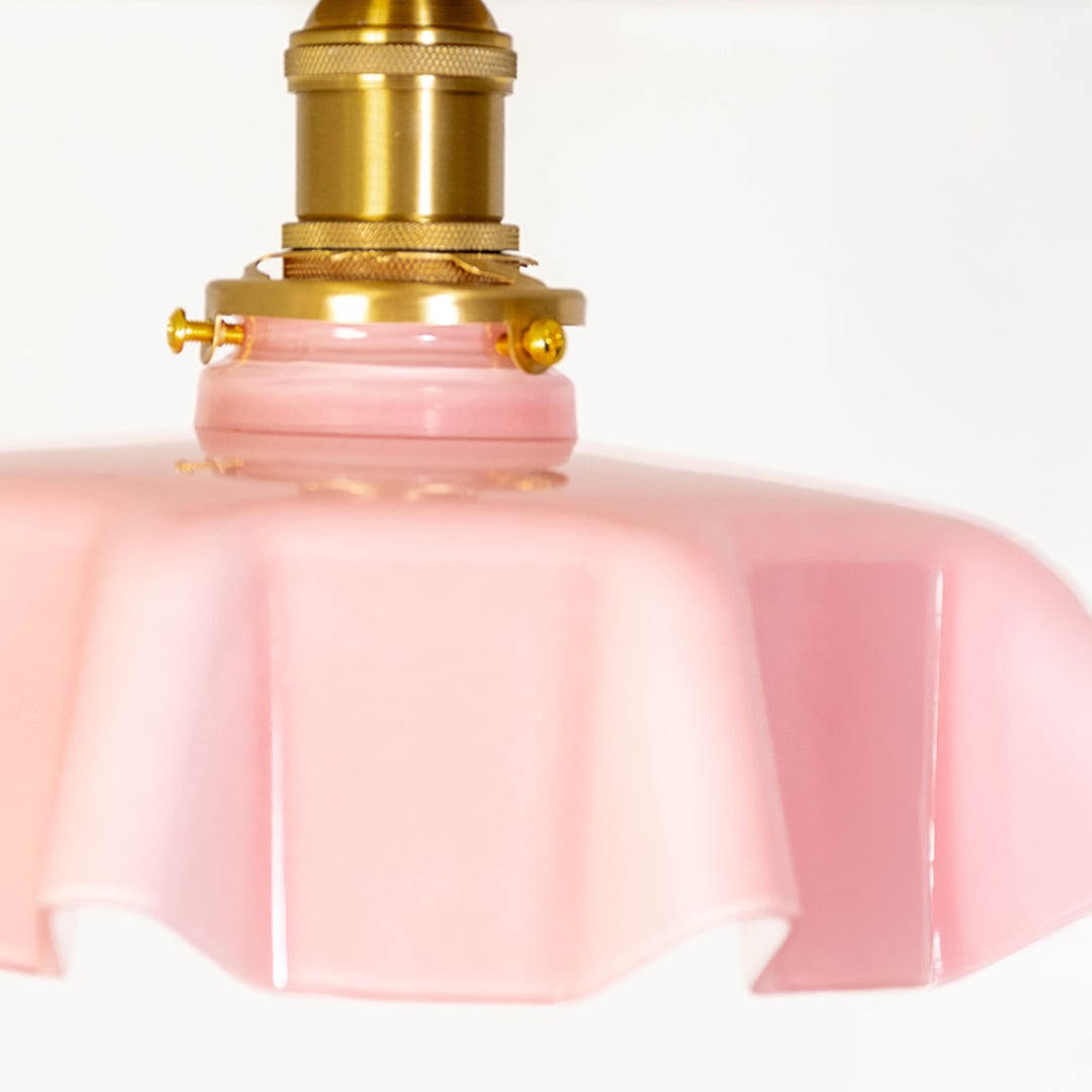 Closeup of pink ruffled glass ceiling light with gold metal mount highlighting the soft glow and elegant finish.