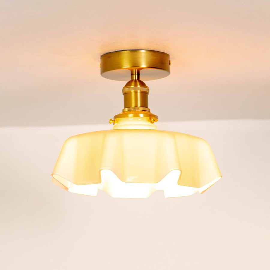Pink glass ceiling light illuminated on a white background showing warm ambient glow and stylish metal mount.