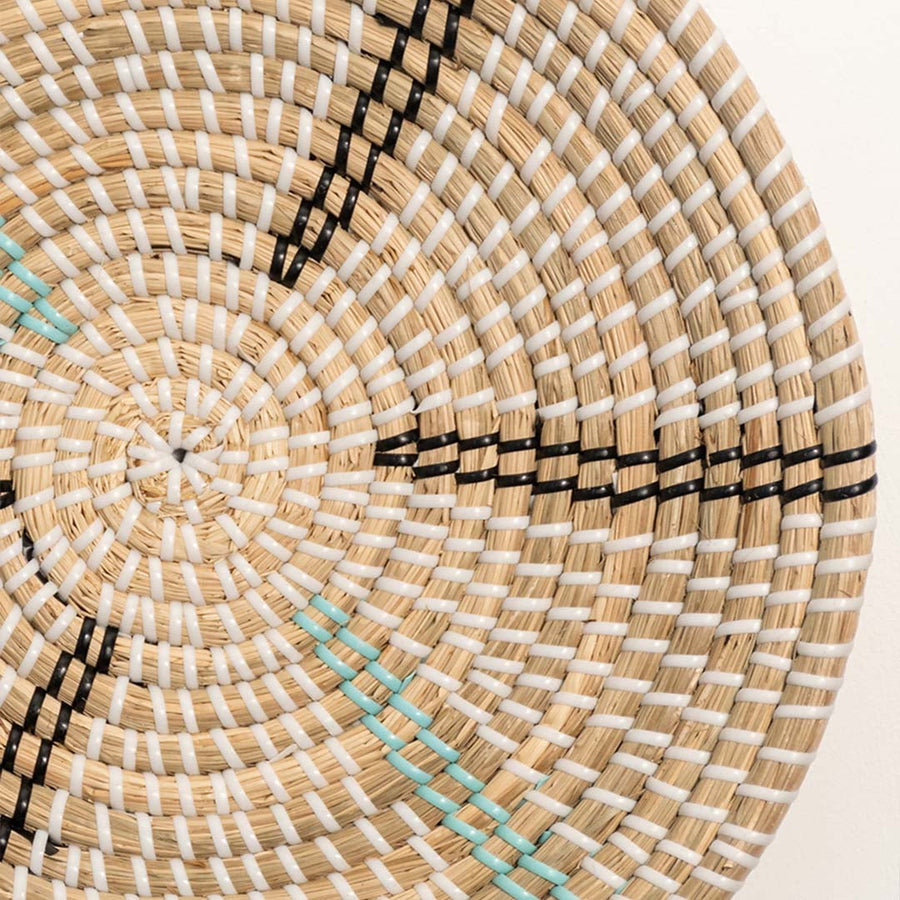Detailed close-up of a woven wall basket showing intricate rattan weaving and subtle turquoise accent lines.