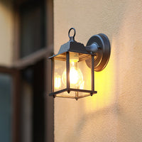 A compact black outdoor wall light glowing warmly on a textured wall creating a soft ambient light that enhances the exterior space during the evening.