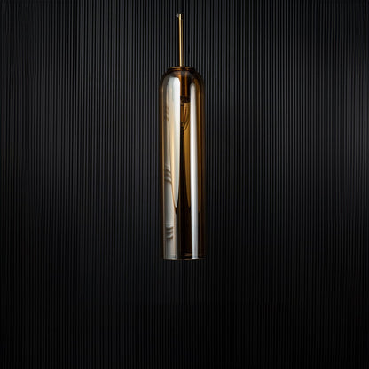 A cylindrical pendant light shown against a deep black background emphasizing its smooth reflective glass surface and modern silhouette with the light off.