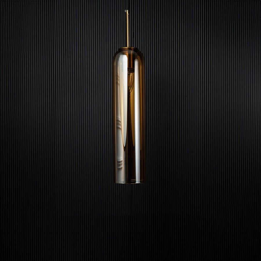 A cylindrical pendant light shown against a deep black background emphasizing its smooth reflective glass surface and modern silhouette with the light off.