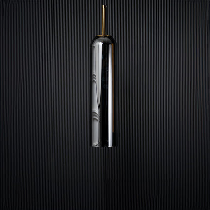A tall silver cylindrical pendant light displayed on a black background with the light turned off emphasizing its glossy surface and slim elegant silhouette.