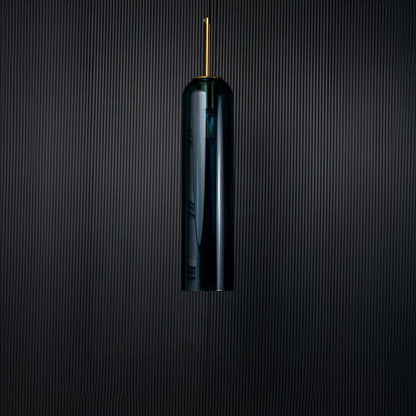 A blue glass pendant light turned off on a solid black background presenting its smooth cylindrical shape and rich blue tone with subtle gold features.
