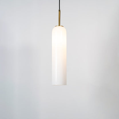 A tall cylindrical pendant light with the light on glowing warmly through the glass shade against a clean white background for a bright contemporary look.
