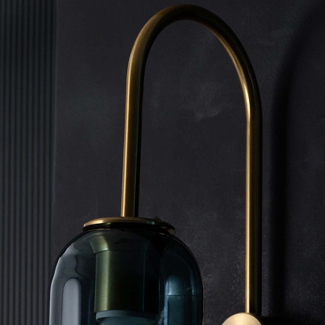 Detailed closeup of teal glass and gold wall light highlighting its tall cylinder shade and polished metal accents for luxurious contemporary decor.