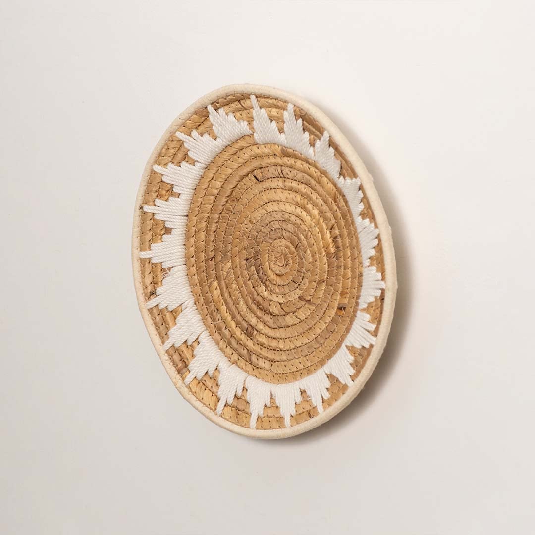 Side profile of the flat woven wall basket showing the thick natural fiber coils and white wrapping details on a white surface.