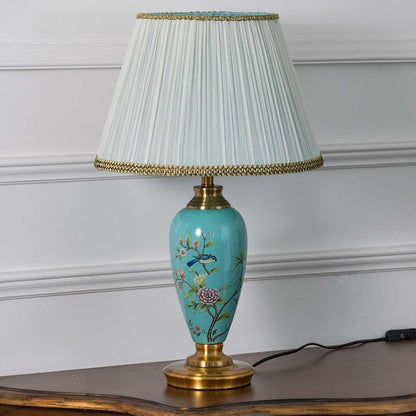 Turquoise floral ceramic table lamp with pleated fabric shade offering elegant traditional decor and ambient lighting indoors.