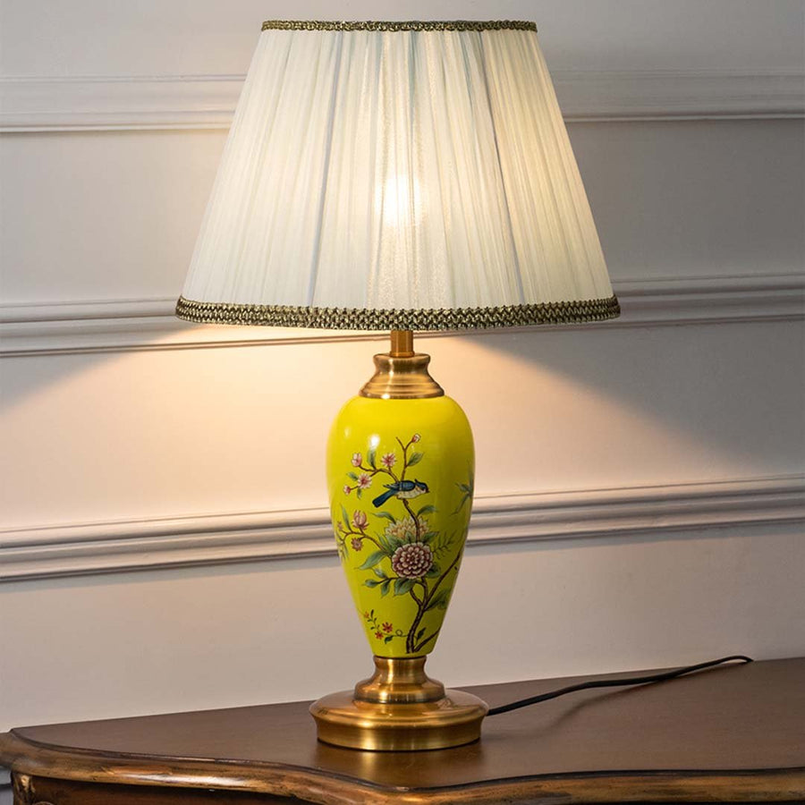 Yellow floral ceramic table lamp with pleated fabric shade offering refined traditional decor and cozy ambient lighting indoors.