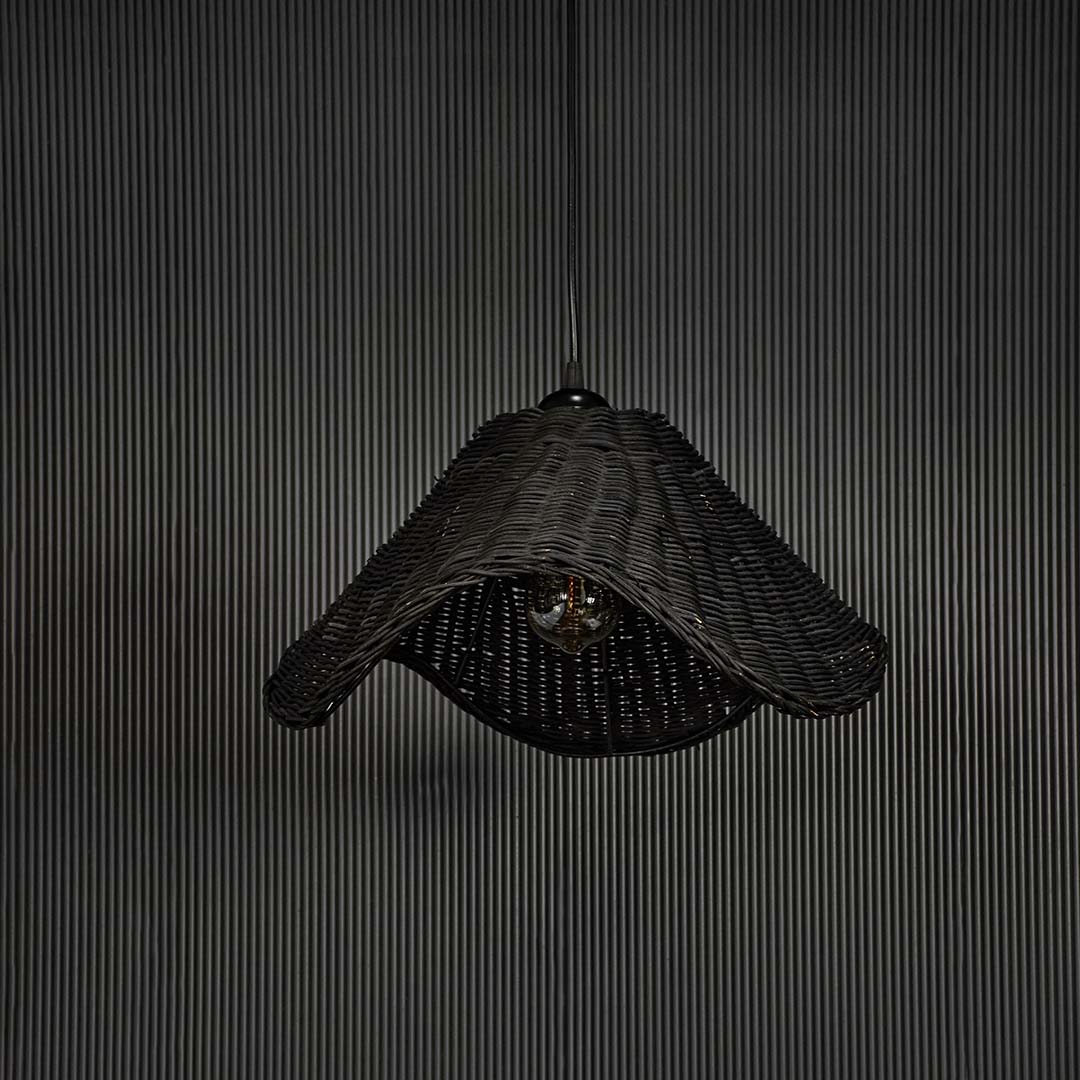 Black rattan pendant light on black background highlighting its sculptural form and fine weave detailing.