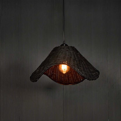 Black rattan pendant light glowing warmly against black background creating a dramatic modern look.