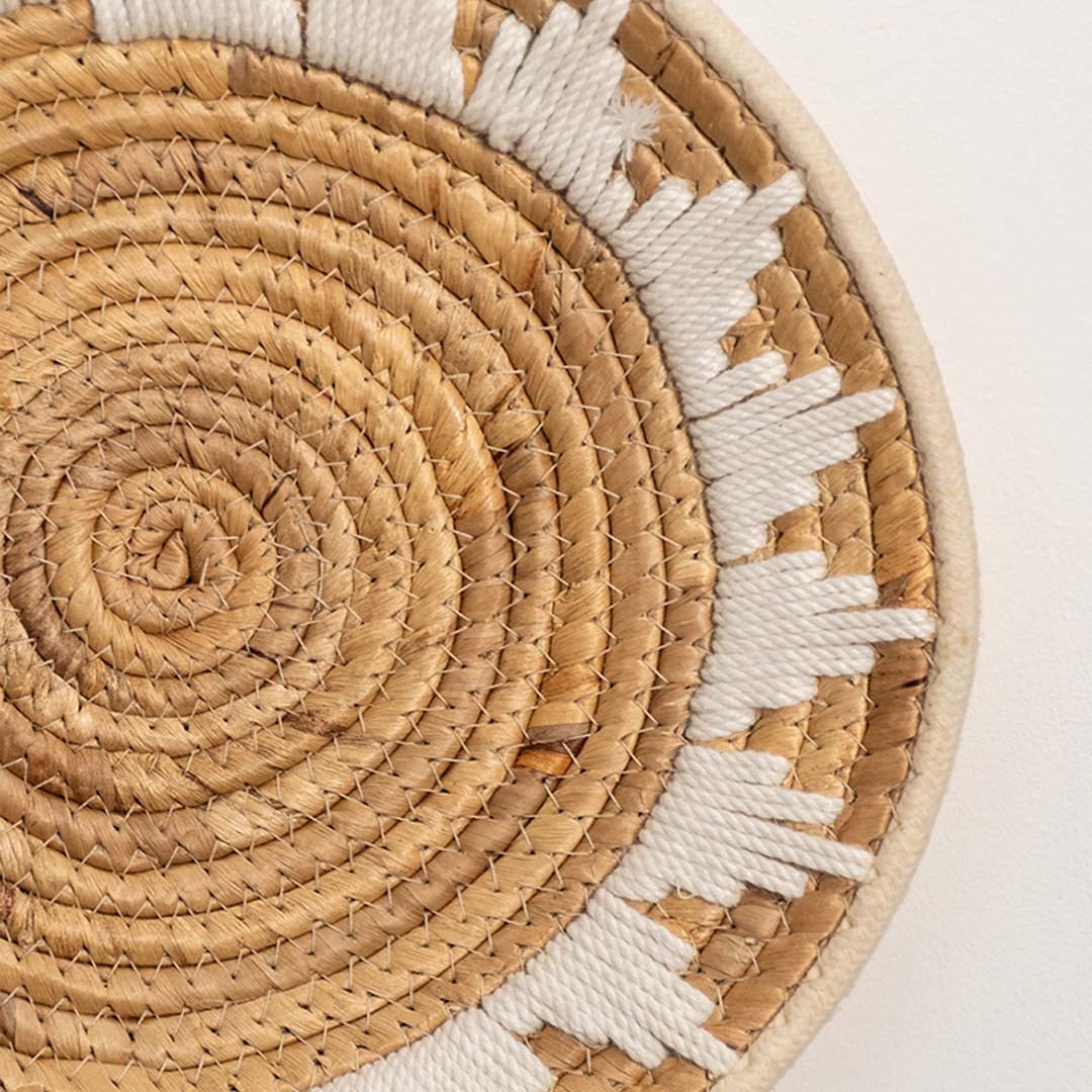 Detailed closeup view of the tight coil weaving and white wrapped sections on the natural seagrass wall basket surface quality.