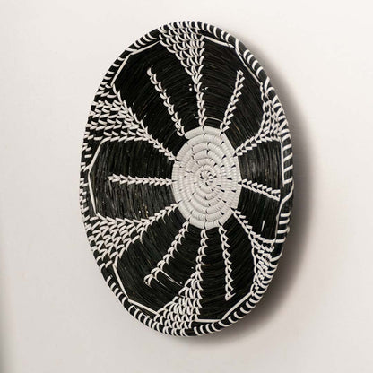 Side profile of the flat woven wall basket showing the natural fiber texture and thin rim design on a white surface for quality check.