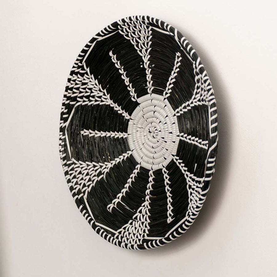 Side profile of the flat woven wall basket showing the natural fiber texture and thin rim design on a white surface for quality check.