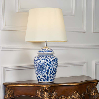 Blue and white floral ceramic table lamp glowing softly on a clean white background highlighting its classic shape and warm light.