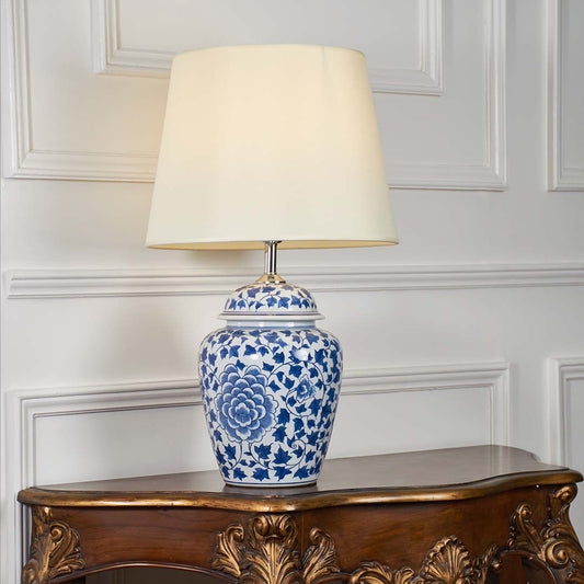 Blue and white floral ceramic table lamp glowing softly on a clean white background highlighting its classic shape and warm light.
