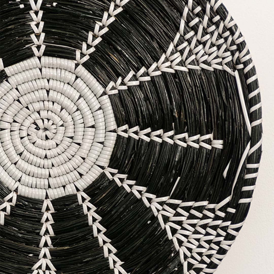 Detailed closeup view of the tight weaving and painted black and white sections on the natural seagrass wall basket surface quality.