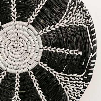 Detailed closeup view of the tight weaving and painted black and white sections on the natural seagrass wall basket surface quality.