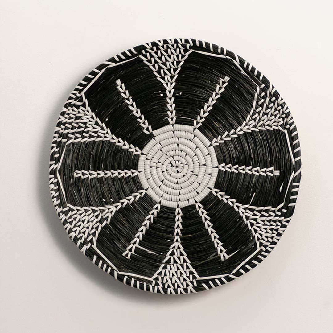 Black and white woven decorative wall basket with radial geometric pattern for artistic wall styling and home decor.
