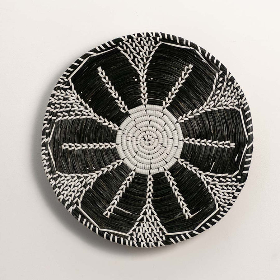 Black and white woven decorative wall basket with radial geometric pattern for artistic wall styling and home decor.