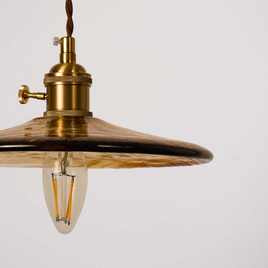 Closeup of brass metal pendant light with clear glass shade highlighting refined vintage craftsmanship.