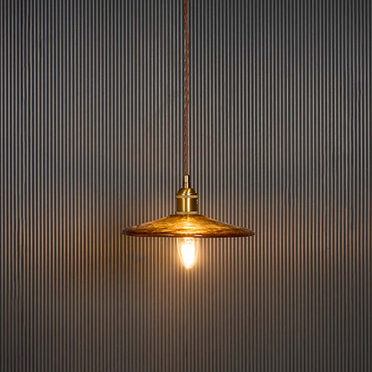 Elegant brass pendant light illuminated against a black background showing warm glow through the metal shade ideal for vintage interiors.