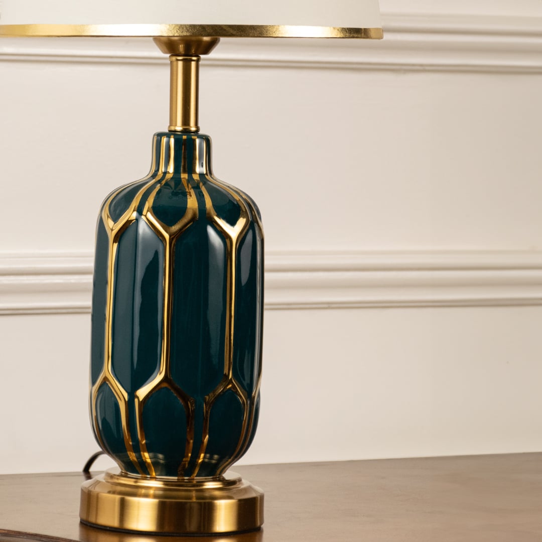 Table lamp closeup showing green ceramic base with gold detailing and white shade for refined interior styling.