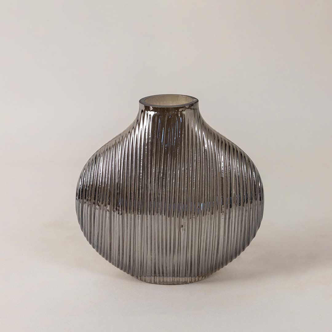 Elegant smoky glass vase with ribbed detailing and smooth round silhouette placed on a plain white surface for a minimal look.