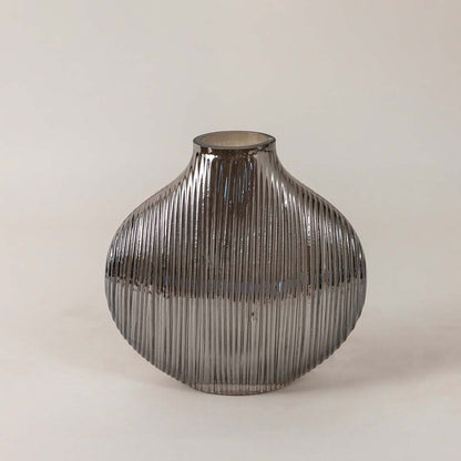 Elegant smoky glass vase with ribbed detailing and smooth round silhouette placed on a plain white surface for a minimal look.
