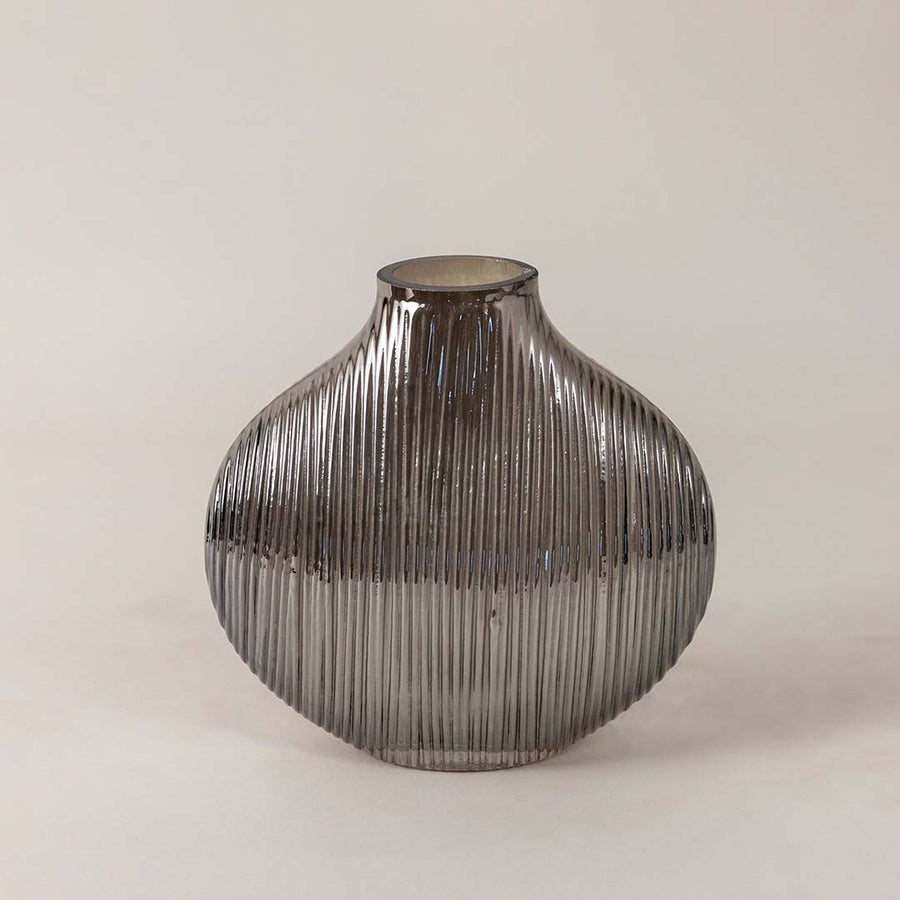 Elegant smoky glass vase with ribbed detailing and smooth round silhouette placed on a plain white surface for a minimal look.