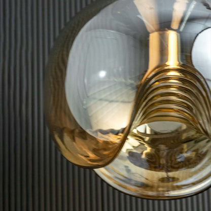Closeup close view of the glass pendant light revealing the swirling wave design and warm glowing core that adds softness and elegance to the fixture.