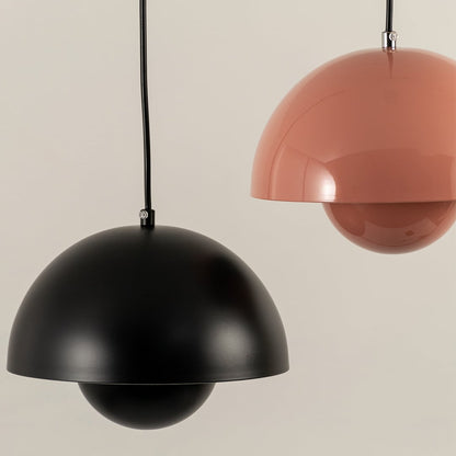 Closeup of grouped dome pendant lights in terracotta black white and mustard hues highlighting their smooth metal finish and modern rounded shapes.