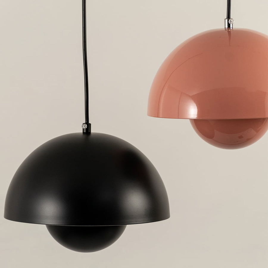 Closeup of grouped dome pendant lights in terracotta black white and mustard hues highlighting their smooth metal finish and modern rounded shapes.