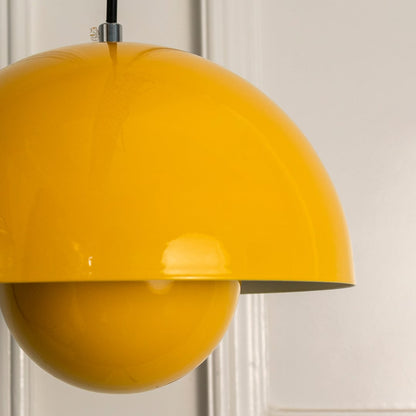 Closeup of yellow metal dome pendant light showing smooth curved surface glossy finish and bold modern lighting design detail.
