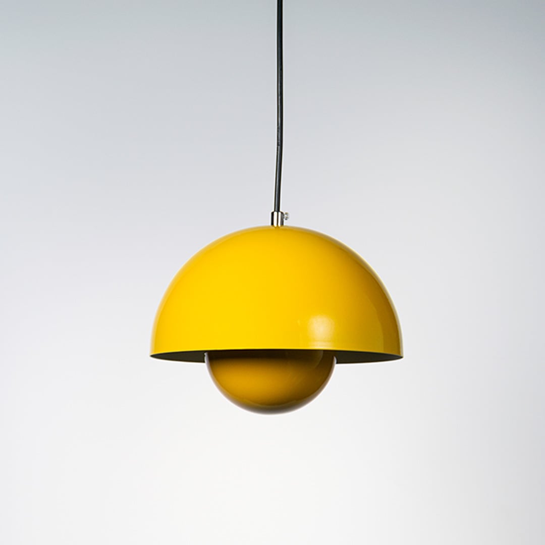 Yellow dome pendant light turned off with smooth curved design glowing gently against a plain white backdrop.