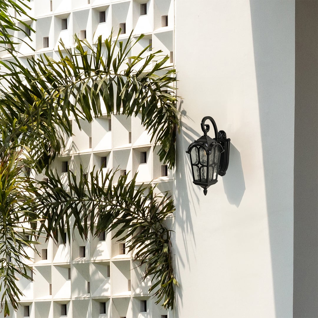 Decorative outdoor wall lantern shown in a lifestyle setting with elegant curves and clear patterned glass.