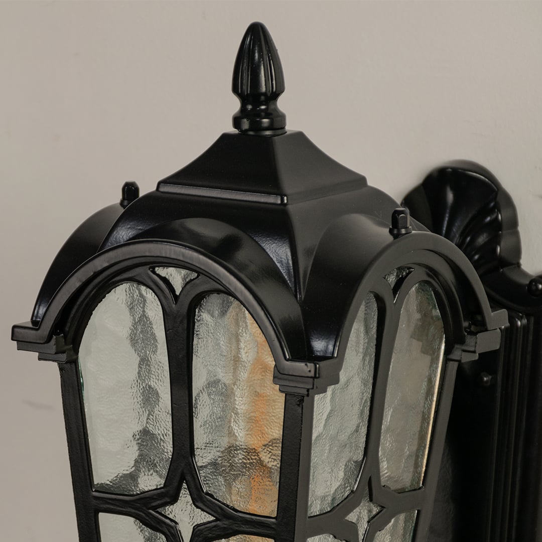 Closeup view of the black outdoor lantern showing detailed curves and clear patterned glass panels.