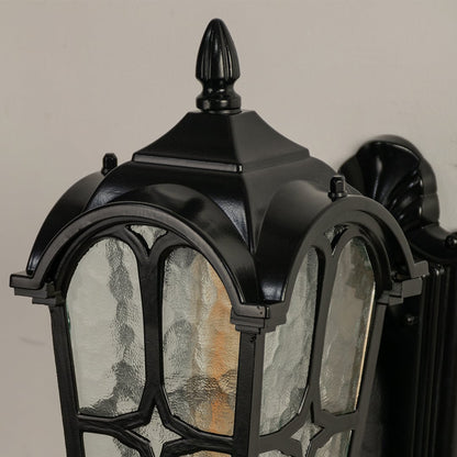 Closeup view of the black outdoor lantern showing detailed curves and clear patterned glass panels.