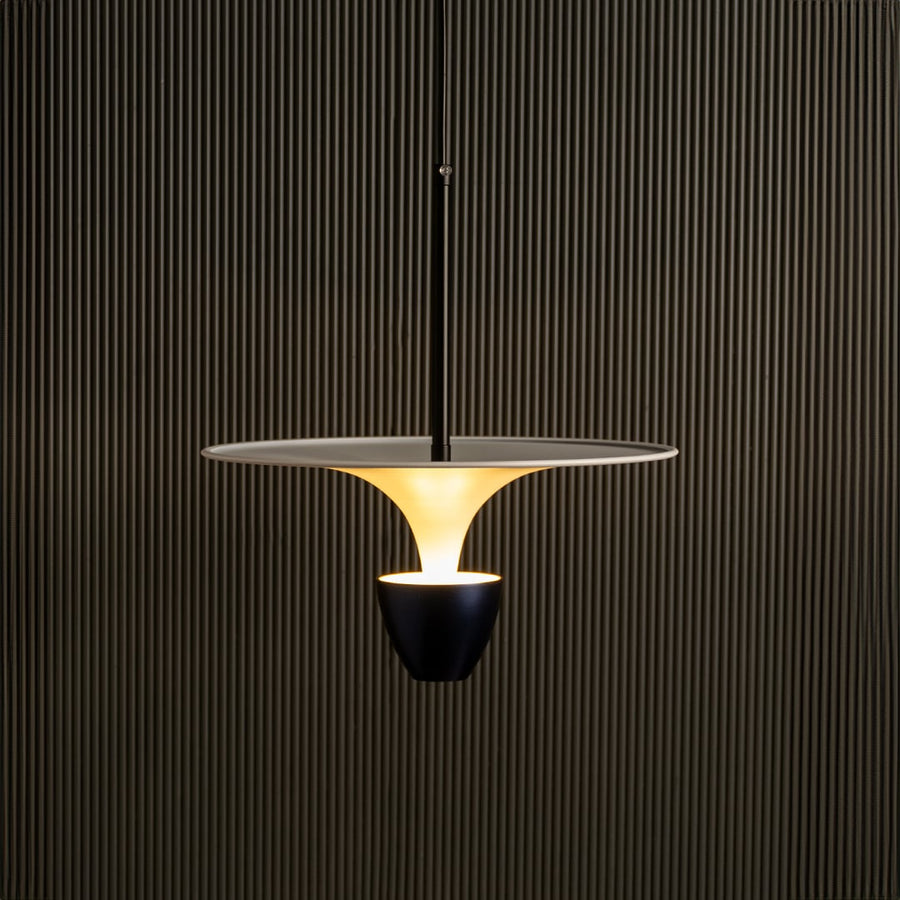 Gold metal pendant light illuminated warmly creating luxurious ambiance for modern indoor spaces.