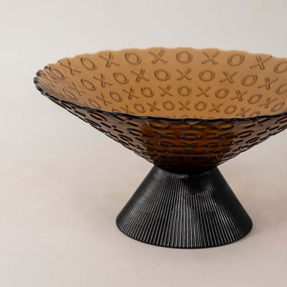 Closeup of amber glass bowl highlighting its embossed XO pattern  smooth glass finish  and ribbed conical black base design.