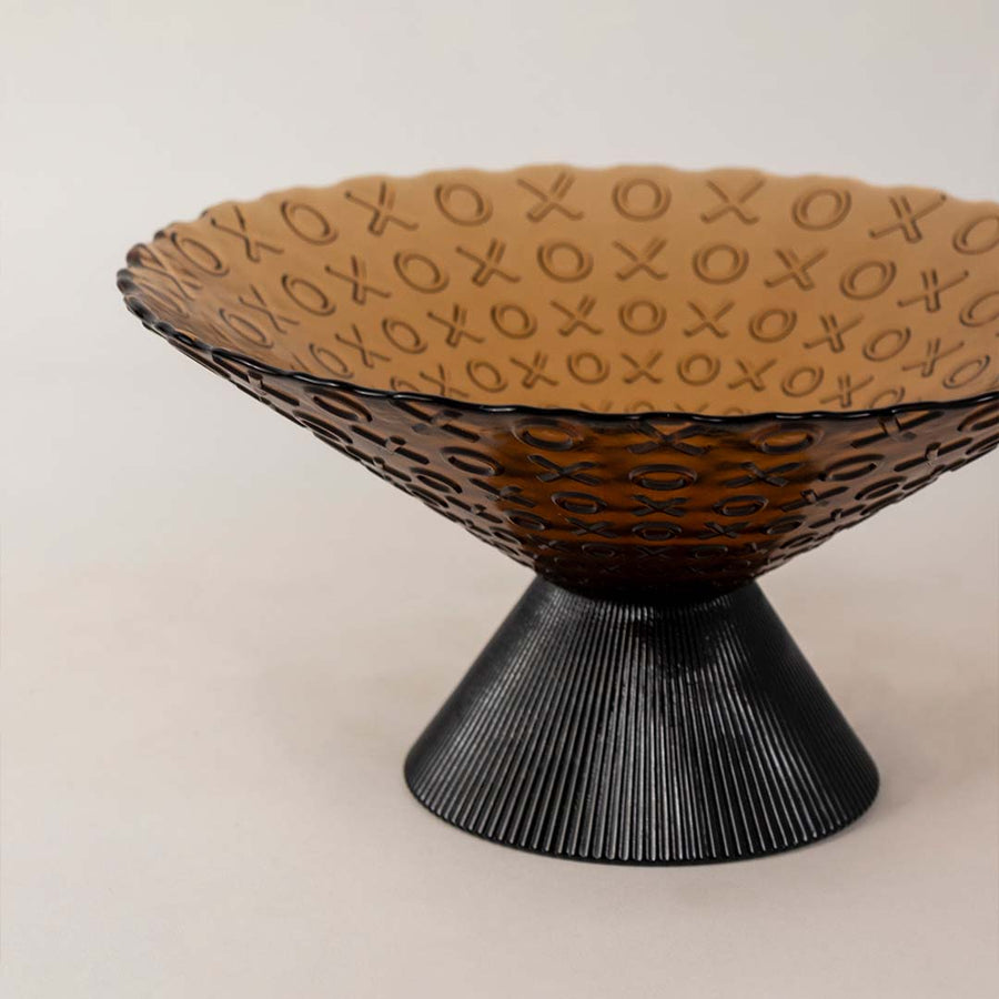 Closeup of amber glass bowl highlighting its embossed XO pattern  smooth glass finish  and ribbed conical black base design.