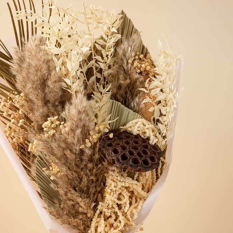 A rustic natural beige dried flower bouquet with pampas grass and a dark brown lotus pod for bohemian tabletop vase decor.