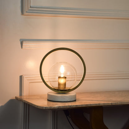 Circular metal table lamp with exposed bulb design creating warm ambient lighting for modern living spaces.