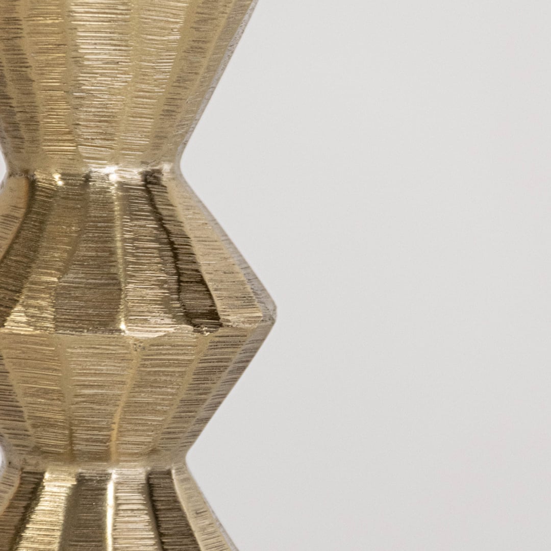 Closeup of gold metal candle holder showing textured geometric detailing for modern living room and dining decor.